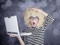 Portrait of funny girl in blonde wig with laptop. Studio shot. Royalty Free Stock Photo