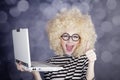 Portrait of funny girl in blonde wig with laptop. Royalty Free Stock Photo