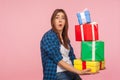 Portrait of funny girl carrying lot of heavy present boxes and looking at camera with amazed comical expression