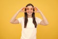 Portrait of a funny girl wearing cool party glasses. Cheerful young girl smiling with heart-shape glasses on yellow Royalty Free Stock Photo