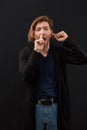 Portrait of a funny guy with finger in his nose and ear against black background. Royalty Free Stock Photo