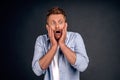 Portrait of funny handsome bearded man with red hair, expressing shock or being terrified of something, standing with opened mouth