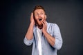 Portrait of funny handsome bearded man with red hair, expressing shock or being terrified of something, standing with opened mouth