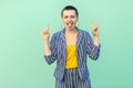 Portrait of funny handsome beautiful short hair young stylish woman in casual striped suit standing with rock horns hands and Royalty Free Stock Photo