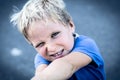 Portrait of a funny happy mischievous cheerful cute blond blue eyed boy making freckles dirty face while playing