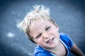 Portrait of a funny happy mischievous cheerful cute blond blue eyed boy making freckles dirty face while playing