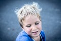 Portrait of a funny happy mischievous cheerful cute blond blue eyed boy making freckles dirty face while playing