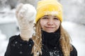 Portrait of funny happy teenage girl in yellow knitted hat plaing with snow outdoors Royalty Free Stock Photo