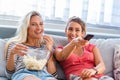 Portrait of funny and happy young women watching comedy in bed and laughing. Cheerful friends eating tasty popcorn and looking Royalty Free Stock Photo