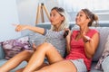 Portrait of funny and happy young women watching comedy in bed and laughing. Cheerful friends eating tasty popcorn and looking Royalty Free Stock Photo