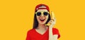 Portrait of funny laughing young woman calling on banana phone on orange background