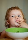 Portrait of funny little baby boy eating from plate holding spoon closeup. Child nutrition concept. Royalty Free Stock Photo