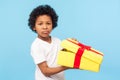 Portrait of funny little boy holding unpacked gift box and looking at camera with upset dissatisfied grimace