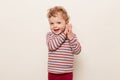 Portrait of funny little girl with blonde hair wearing casual striped turtleneck, having fun, playing, clapping hands, looking at Royalty Free Stock Photo