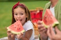 Portrait of funny little girl looking at camera while eating watermelon with her father, family having a picnic in the Royalty Free Stock Photo