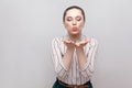 Portrait of funny in love beautiful young woman in striped shirt and makeup and collected ban hairstyle, standing with closed eyes