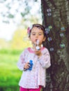 Portrait of funny lovely little girl blowing soap bubbles in the park Royalty Free Stock Photo