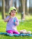 Portrait of funny lovely little girl blowing soap bubbles in the park Royalty Free Stock Photo