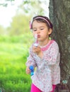 Portrait of funny lovely little girl blowing soap bubbles in the park Royalty Free Stock Photo