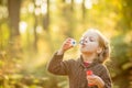 Portrait of funny lovely little girl blowing soap bubbles.Cute blonde blue-eyed girl in yellow knitted coat in the Royalty Free Stock Photo