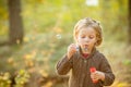 Portrait of funny lovely little girl blowing soap bubbles.Cute blonde blue-eyed girl in yellow knitted coat in the Royalty Free Stock Photo