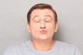 Portrait of funny mature man pouting his lips and blowing kiss