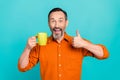 Portrait of funny middle age brunet hair businessman wear orange shirt thumb up rate tasty holding coffee isolated on Royalty Free Stock Photo