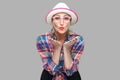 Portrait of funny modern stylish mature woman in casual style with hat and eyeglasses standing sending kiss and looking at camera