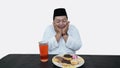 Portrait of overweight muslim man with head cap or songkok pray before eat and drink for islam break fasting Royalty Free Stock Photo