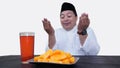 Portrait of overweight muslim man with head cap or songkok pray before eat and drink for islam break fasting Royalty Free Stock Photo