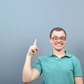 Portrait of funny nerd with big eyes having an idea  and showing at empty space above against gray background Royalty Free Stock Photo