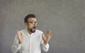 Portrait of funny nerd man in glasses with surprised facial expression on gray background. Royalty Free Stock Photo