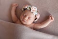 Cute newborn baby girl wearing flower headband peacefully sleeps in funny position. Royalty Free Stock Photo