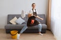 Portrait of funny optimistic female washing floor with mop at home, doing domestic chores and having fun, dancing with cleaning Royalty Free Stock Photo