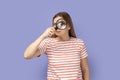 Funny positive woman standing, holding magnifying glass and looking at camera with big zoom eye. Royalty Free Stock Photo