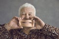 Funny senior man covering face with mobile phone with magnified picture of perfect smile Royalty Free Stock Photo