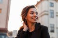 Portrait of a funny pretty happy beautiful young woman with a cute smile in a fashionable black coat outdoors in the city Royalty Free Stock Photo