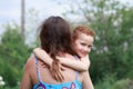 Portrait of funny redhead boy with freckles hugs his mom around the neck