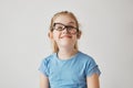 Portrait of funny small girl with blue eyes and light hair in blue shirt having fun with father`s glasses. Happy