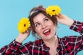 Portrait of a funny smiling pretty young woman in a red checkered shirt substituting yellow flowers to her head posing Royalty Free Stock Photo