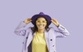 Portrait of funny stylish ethnic woman smiling broadly isolated on pastel purple background.
