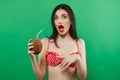 Portrait of Funny Surprised Brunette in Bright Swimwear with Tropical Cocktail in Hands on Green Background. Royalty Free Stock Photo