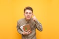 Portrait of a funny surprised nerd in glasses on a yellow background, holds a notebook, books and pen in his hand, looks intently Royalty Free Stock Photo