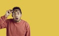Portrait of funny surprised young man looking at you with shocked expression on yellow background. Royalty Free Stock Photo