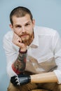 Portrait of a thoughtful man with prosthetic bionic arm over blue background