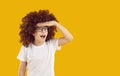 Portrait of funny, toothless, amazed teenager in transparent glasses and a curly wig