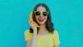 Portrait funny woman calling on a banana phone on a blue background Royalty Free Stock Photo