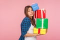 Portrait of funny woman carrying lot of heavy present boxes falling on her, looking with comical surprised grimace