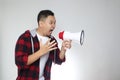 Portrait of funny young Asian man shouting with megaphone, mad yelling screaming crazy supporting motivating