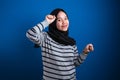 Portrait of a funny young Asian muslim girl wearing hijab dancing happily joyful expressing celebrating good news Royalty Free Stock Photo